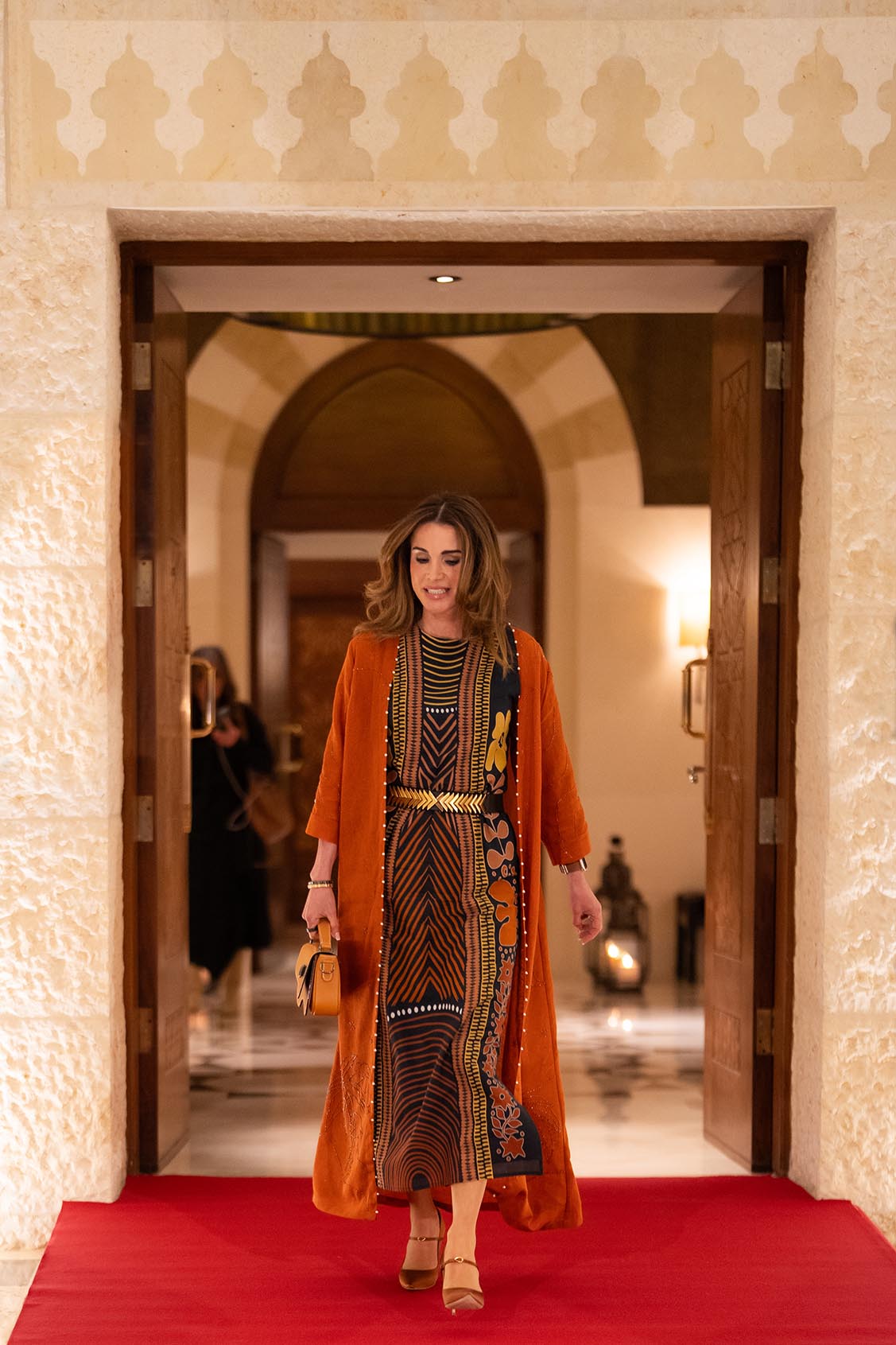 إطلالة الملكة رانيا بعباءة بستايل شرقي باللون البرتقالي من توقيع دار الأزياء اللبنانية Sarah’s Bag.