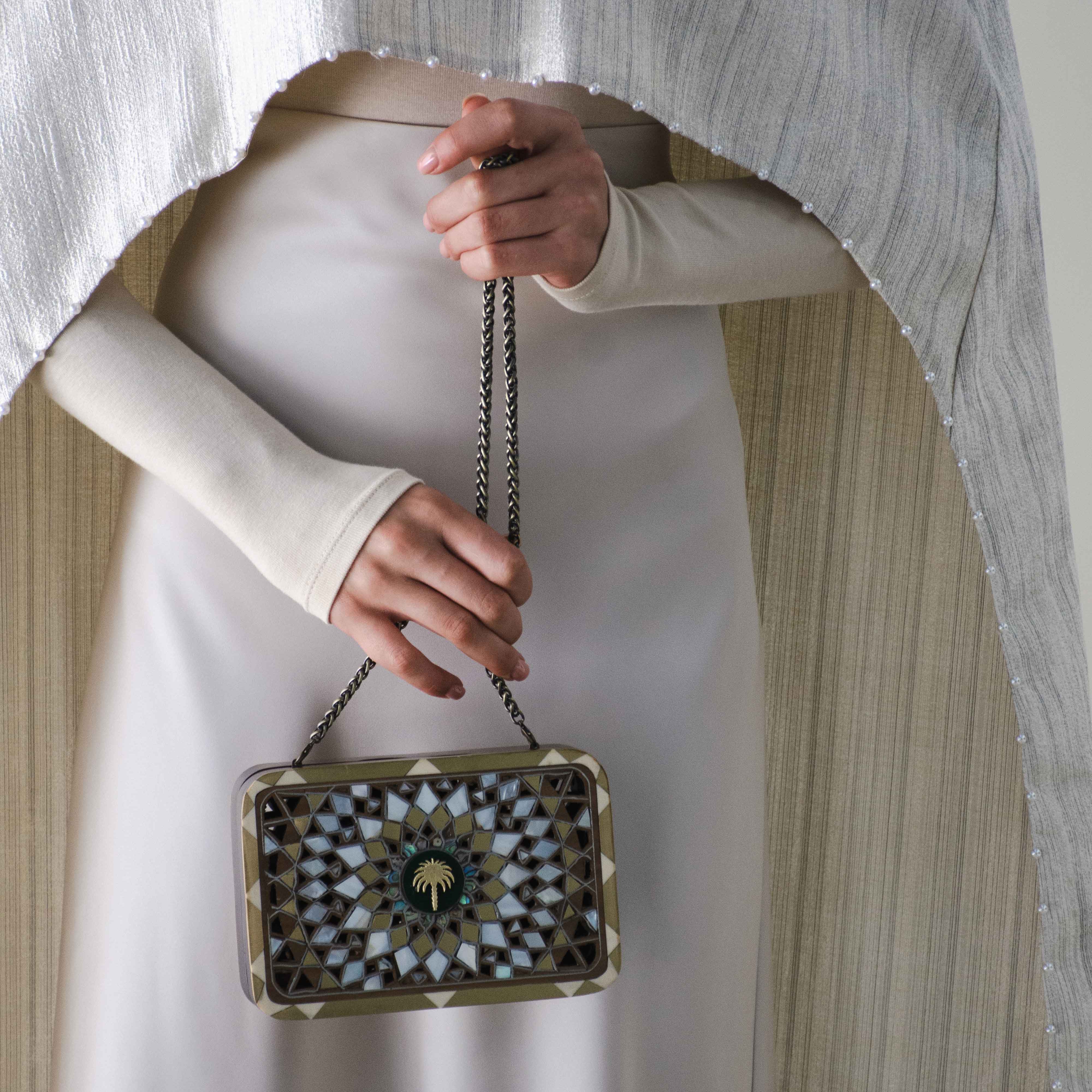 Person holding a decorative handbag with a plain background