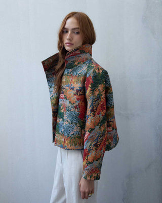 Woman wearing a autumn patterned jackrt against a plain background