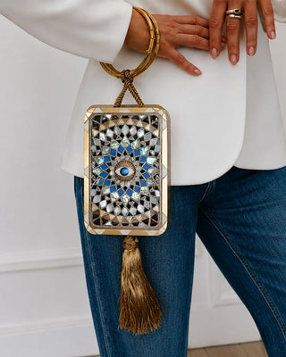 Decorative handbag with intricate design held by a person wearing a white top and blue jeans.