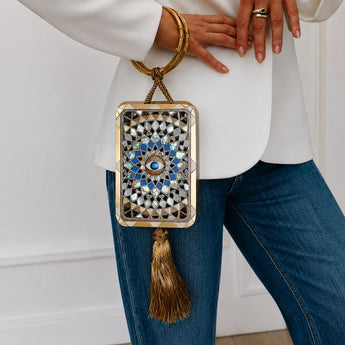 Decorative handbag with intricate design held by a person wearing a white top and blue jeans.