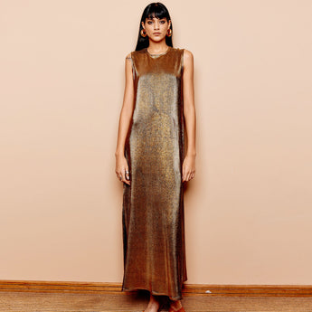 A model wearing a bronze sleeveless maxi dress with a pleated texture, standing against a plain background.
