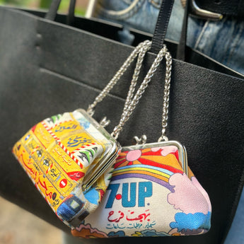 A colorful handbag charm designed to resemble a decorated Middle Eastern truck, with a yellow base and decorative elements in red, blue, and green, featuring text and artistic print.