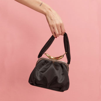 A black handbag with a metallic clasp and a textured surface, viewed from the front.