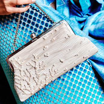 Silver pearl clutch bag on a blue textured surface