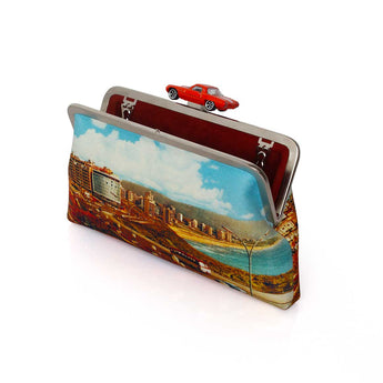 A classic bag featuring a colorful scenic print of a coastal city with a river, mountains, and a red car on top, set against a plain white background.