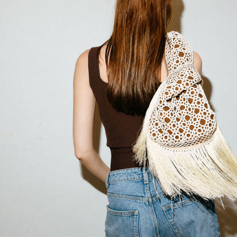 Person holding a white crocheted clutch bag on havane  slip bag on a white background
