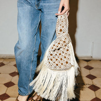 Person holding a white crocheted clutch bag on havane  slip bag on a white background