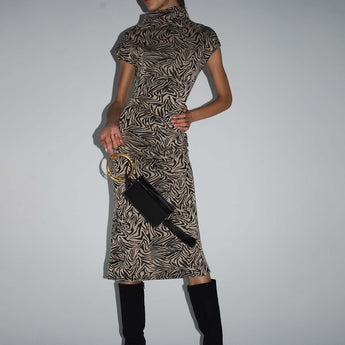 A black lacquered wristlet with a glossy finish and a black tassel, featuring twin gold bracelet handles.