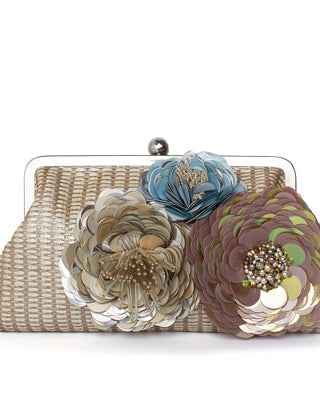 A straw handbag with floral embellishments in pastel colors.