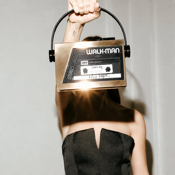 Person holding a vintage Walkman bag against a plain background