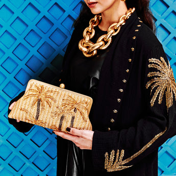 A gold clutch purse with a palm tree design, hand-beaded with radiant gold glass beads.