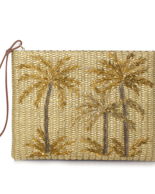 A gold straw clutch with gold palm trees beadwork and a brown leather wrist strap.