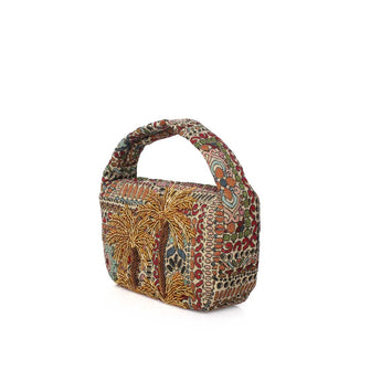 A small structured handbag with a top handle, covered in a dense batik-style pattern featuring red, green, gold, beige, and brown tones, shown on a plain white background.