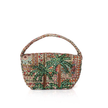 A small structured handbag with a curved top handle, featuring an intricate multicolor batik-style pattern with prominent green palm tree motifs, set against a plain white background.