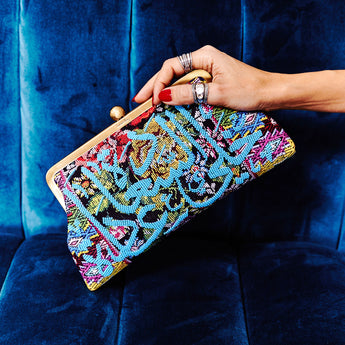 A model holding a blue calligraphy on floral classic clutch bag with shoulder chain