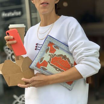 Pouch with decorative design and tassel in the hands of a model