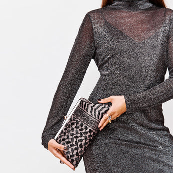 Black on black keffiyeh patterned clutch bag on model.