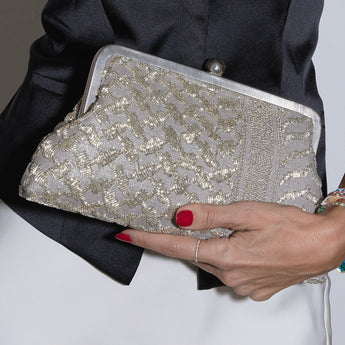 Silver keffiyeh design beaded with silver beads clutch bag in a model's hands