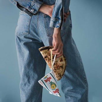 Triangle-shaped bonjus bag with ananas design and text held by a model