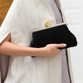 Women holding a black clutch purse with a moon gold clasp.