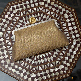 Gold classic clutch bag with a moon clasp on a decorative wooden table