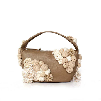 Beige leather handbag with crocheted moss details on a white background