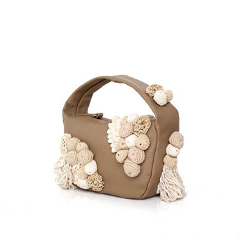 Beige leather handbag with crocheted moss details on a white background