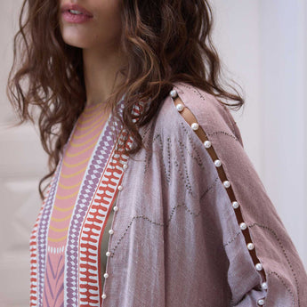 Close-up of a person wearing a patterned garment with pearl embellishments.