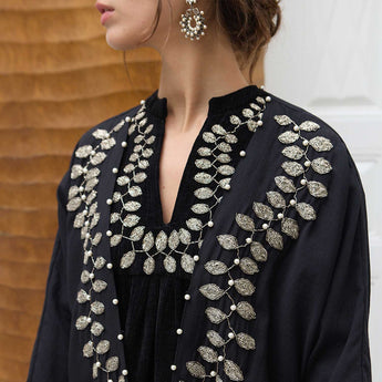 Black outfit with intricate silver embroidery on a blurred background