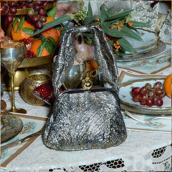 Gold metallic handbag with a pomegranate clasp on a a table