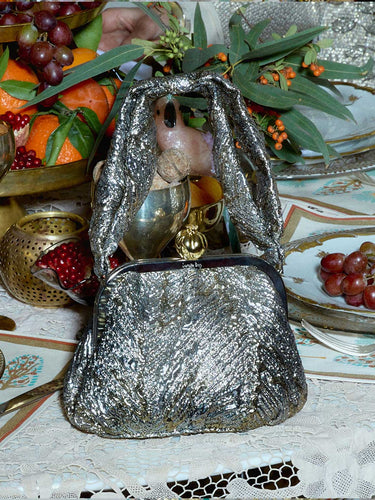 Gold metallic handbag with a pomegranate clasp on a a table