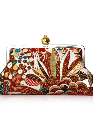 Colorful floral and leaf patterned handbag topped with a pomegranate clasp on a white background