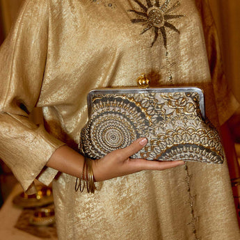 Women is holding Elegant clutch bag with sunburst gold and black pattern 