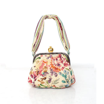 Floral patterned handbag with a colorful handle on a white background