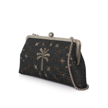 A black clutch bag with a silver-tone metal frame and chain strap, decorated with a silver palm tree and small star motifs embellished with brown and gold rhinestones.