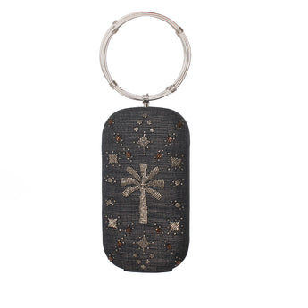 A dark gray woven clutch bag with a silver-tone metal ring handle, decorated with a central palm tree motif and scattered star patterns in silver and brown rhinestones.