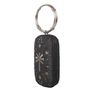 A dark gray woven clutch bag with a silver-tone metal key ring, decorated with a silver palm tree motif and scattered rhinestone star accents.