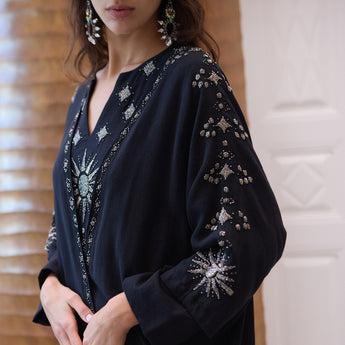 Black embellished garment with star patterns on a neutral background