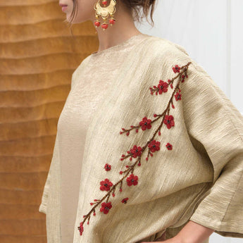Beige abaya with red floral embroidery on a neutral background