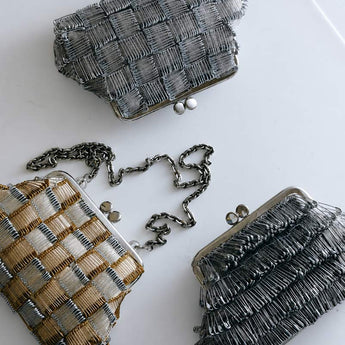 Three woven handbags with metallic accents on a white surface