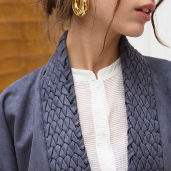 Close-up of a person wearing a navy blue jacket over a white top.