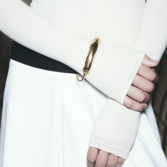 Person wearing a white long-sleeve top and white skirt with a gold zipper detail.